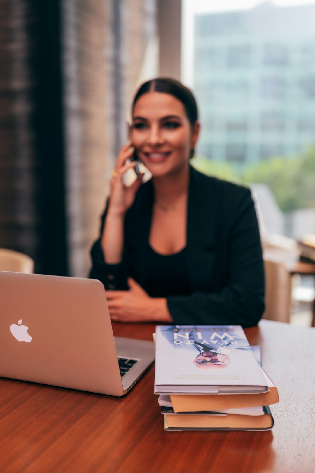 Businesswoman sitting at heer desk, behind her laptop, having a call on her mobile phone.